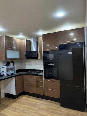 Eine moderne Küche mit Holzausstattung, Edelstahlgeräten und einem schwarzen Kühlschrank.