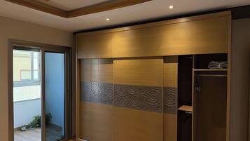 Una habitación con puerta corrediza que da a un balcón, un armario con panel decorativo y techo con vigas de madera.