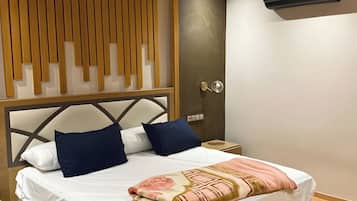 Un dormitorio moderno con techo de listones de madera, cama con sábanas blancas y almohadas azules, mesita de noche de madera y un equipo de aire acondicionado de pared.