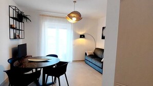 Un salon moderne comprenant un coin repas, un canapé, une table basse et un luminaire suspendu.