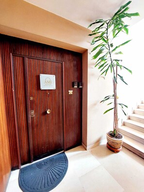 A wooden door with a sign, a potted plant, and a blue mat. - Finely renovated Skyline apartment adjacent to Garbatella Park (Roma)