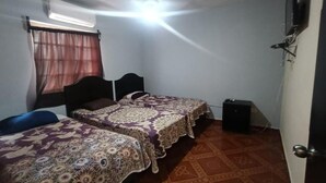 Ein Zimmer mit zwei Betten, einem Deckenventilator, einer Klimaanlage, einer Tür und einem gemusterten Boden.