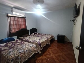 Habitación con dos camas, ventilador de techo, aire acondicionado, una puerta y piso con diseño.