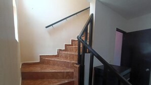 Eine Treppe mit Holzstufen und schwarzen Geländern, die zu einem dunklen Raum mit einem Flachbildfernseher führt.
