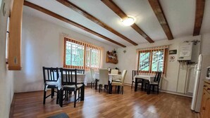Un espace repas avec des chaises et des tables en bois, un plancher en bois et un plafond avec des poutres apparentes.