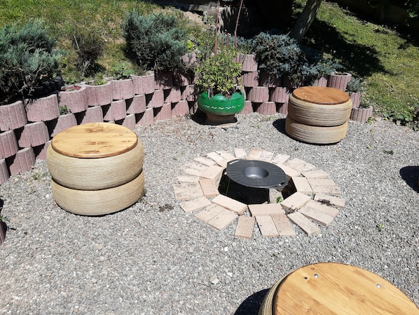 A circular seating area with a fire pit, surrounded by a brick wall and gravel ground.