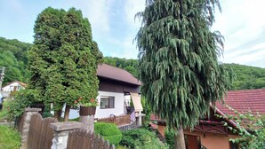 Une maison avec un toit rouge, une clôture en bois et un grand arbre dans la cour.