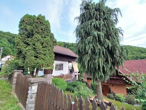 A house with a red roof, a wooden fence, and a large tree in the yard.