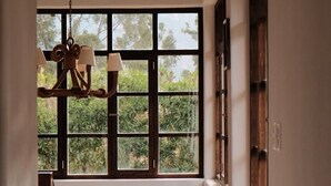 Un pasillo con una escalera de madera, una lámpara de araña colgante y un amplio ventanal con vistas al verdor.