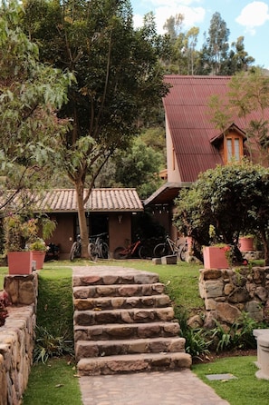 A house with a red roof, stone steps leading to a door, and bicycles parked outside. - The Lodge Peru (Lamay)
