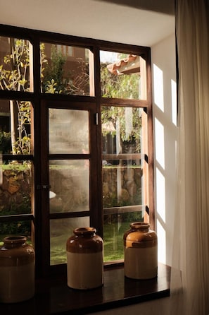 A window with a view of a garden and three ceramic jars on a sill. - The Lodge Peru (Lamay)