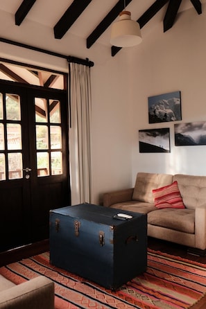 Una habitación con una puerta grande de madera, una maleta azul, un sofá color beige y una alfombra estampada.