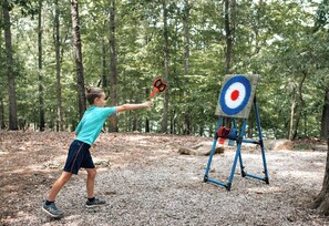 A person aiming at a target in a forested area.