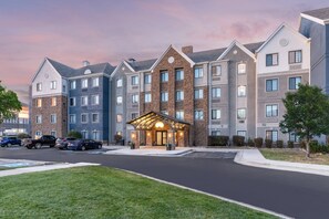 Un hôtel à plusieurs étages doté d’une entrée principale, d’un parking et d’un espace vert.
