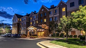 A multi-story hotel with a central entrance, a parking lot, and a well-maintained lawn. - King Studio w/ Kitchen | Hot Breakfast + Pool (Denver)