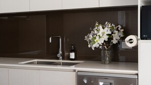 A modern kitchen with a dishwasher, a sink, and a vase with flowers on the counter.