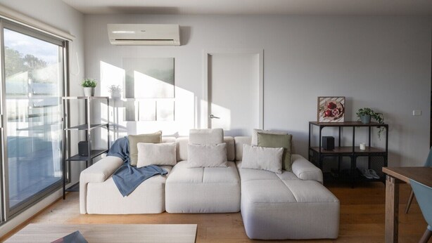 A modern living room with a sectional sofa, a coffee table, a side table, and a large window.