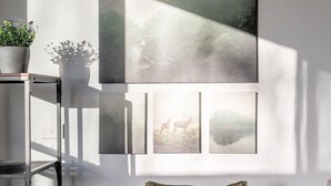 A modern living room with a sofa, pillows, a knitted throw, a plant, and framed pictures on the wall.