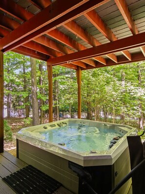 Un jacuzzi bajo una pérgola de madera con vista al bosque.