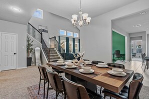 Un comedor con una larga mesa de madera, sillas y una lámpara de araña.