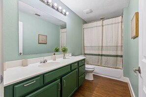A bathroom with a large mirror, two sinks, a toilet, and a shower curtain. - Modern 4BHK Backyard 25 mins FIFA 10 mins Downtown (Dallas)