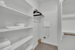 A white closet with shelves, a wooden hanger, and a white box on the wall. - 5-bedroom house in Round Rock with pool access, close to tech hub (Round Rock)
