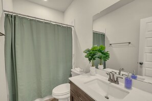 A bathroom with a shower curtain, toilet, sink, mirror, and a potted plant. - 5-bedroom house in Round Rock with pool access, close to tech hub (Round Rock)