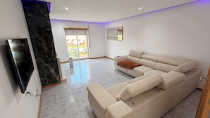Una sala de estar moderna con un sofá modular, un televisor de pantalla plana y una pared de acento de mármol.