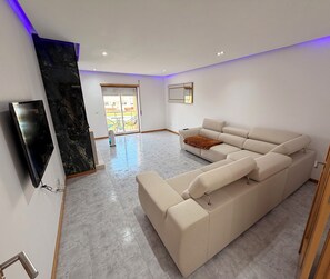 Ein modernes Wohnzimmer mit einer Eckcouch, einem Flachbildfernseher und einer Wand mit Marmorverkleidung.
