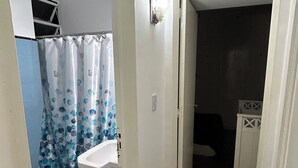 A narrow hallway with a bathroom on the left, featuring a toilet, sink, and shower curtain. - Spacious and bright apartment in parque chas, meters away from subway b (Buenos Aires)