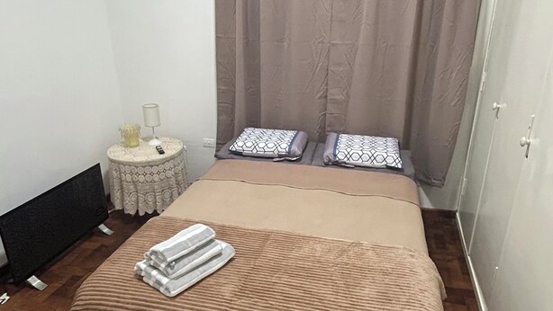 A bedroom with a bed, a bedside table, a lamp, and a wardrobe. - Spacious and bright apartment in parque chas, meters away from subway b (Buenos Aires)