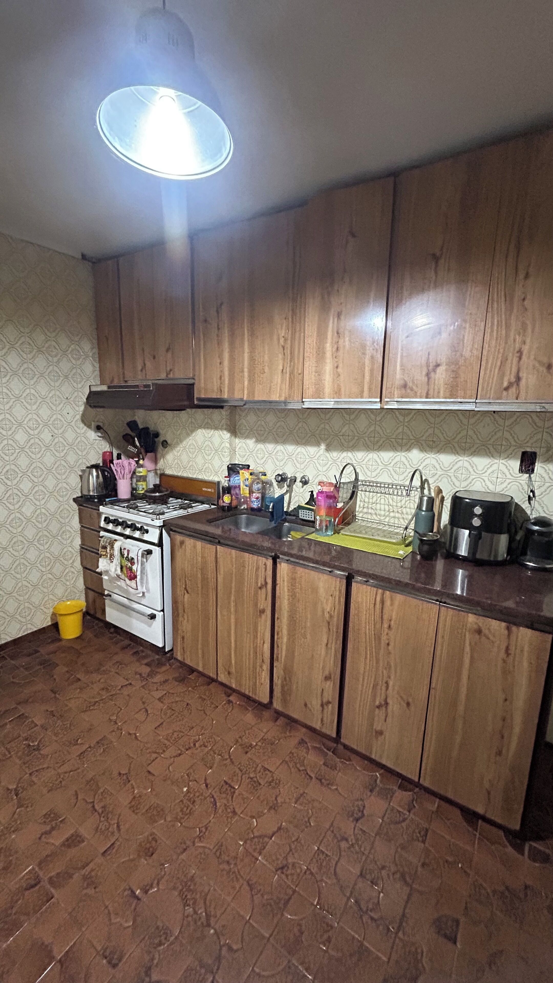 Una cocina con gabinetes de madera, una estufa a gas y varios utensilios de cocina sobre la encimera.