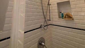Eine Dusche mit Dachfenster, einem Handtuchhalter und Ablagefläche für Toilettenartikel.