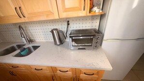 Eine Küche mit Holzschränken, einem Spülbecken, einem Toaster und einem Kühlschrank.