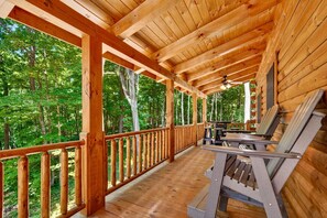 Une terrasse en bois dotée d’une rambarde, d’un ventilateur de plafond et d’un espace salon avec une table et des chaises.