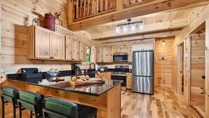Une cuisine de style rustique, avec des éléments en bois, un îlot central, des tabourets de bar et des appareils électroménagers modernes.