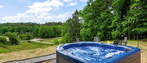 A hot tub with a view of a forest and a pathway.
