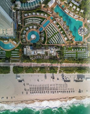 Eine Luftaufnahme eines Resorts mit großem Pool, Strandbereich und mehreren Gebäuden.