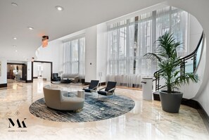 A spacious lobby with a marble floor, a round seating area, and large windows. - FontaineBleau|Ocean View w/ Balcony & Beach Access (Miami Beach)