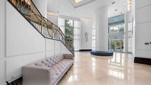 Eine großzügige Lobby mit moderner Treppe, einer Sitzecke und einem großen Glastür-Eingang.