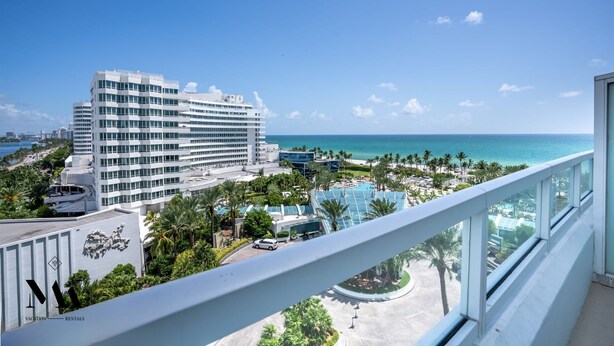 A high-rise hotel with a view of the ocean, a swimming pool, and a parking area. - FontaineBleau | Ocean & Resort View w/ Balcony (Miami Beach)