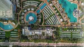 An aerial view of a resort with multiple swimming pools, a beach area with sun loungers, and a beachfront view. - FontaineBleau | Ocean & Resort View w/ Balcony (Miami Beach)
