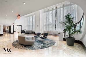 Eine geräumige Lobby mit einer gebogenen Sitzecke, großen Fenstern und einer Zimmerpflanze.