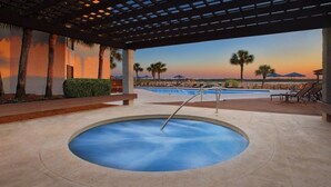 A pool area with a circular hot tub, lounge chairs, and a view of palm trees and a sunset. - Hilton Head Island Escape with Spacious 2BR Villa Near the Beach (Hilton Head Island)