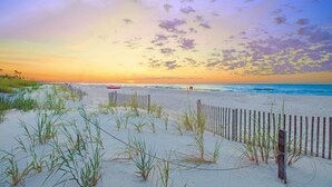 A beach scene with a wooden fence, sand dunes, and a sunset. - Hilton Head Island Escape with Spacious 2BR Villa Near the Beach (Hilton Head Island)