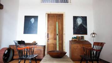Ein Essbereich mit einem Holztisch, zwei Stühlen, einem Holzschrank und zwei gerahmten Kunstwerken an den Wänden.