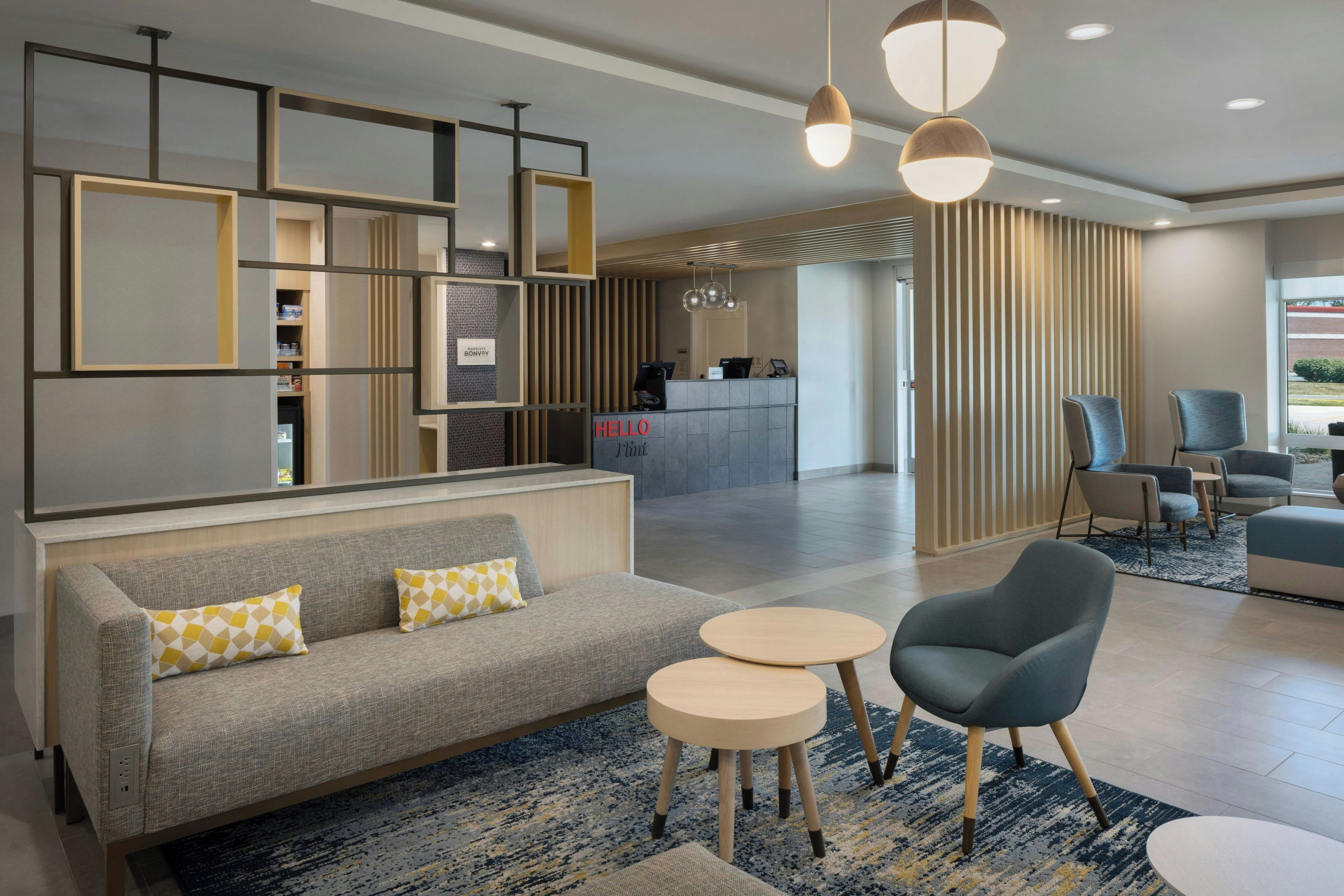 A modern hotel lobby with a reception desk, seating area, and a view of the reception.