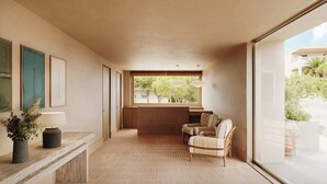 A modern interior with a reception desk, a seating area with a sofa and chairs, a large window with a view of greenery, and pendant lighting. - Sabatic Formentera Autograph Collection (Formentera)