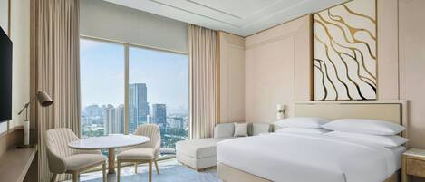 Una habitación de hotel con una cama grande, un sofá, una mesita y un televisor.