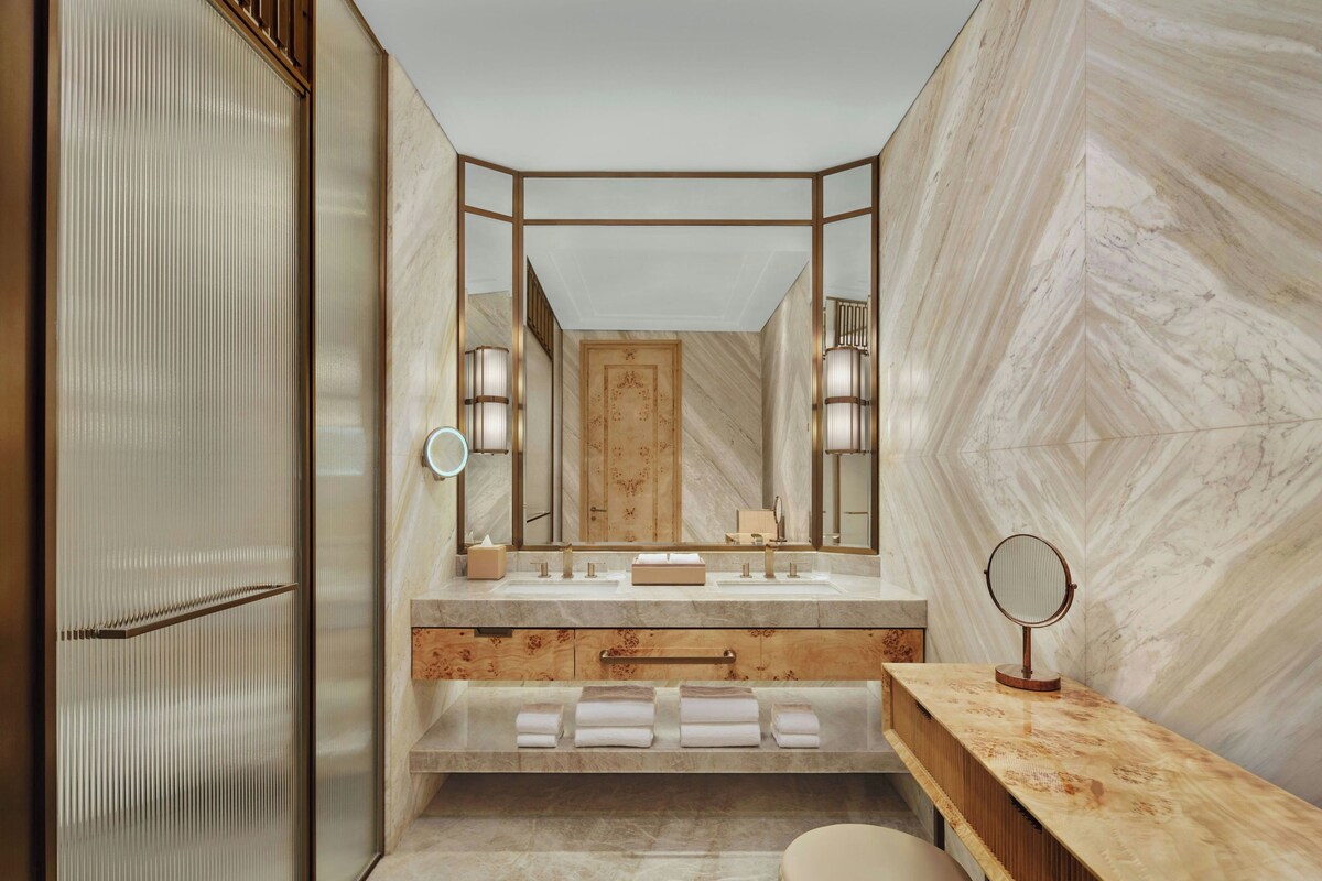 A modern bathroom with a vanity, mirror, and towel rack.